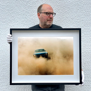 Photograph held by photographer Richard Heeps.  The photograph features a light blue Buick car moving towards the camera and slightly obscured by the dust clouds which it has created.