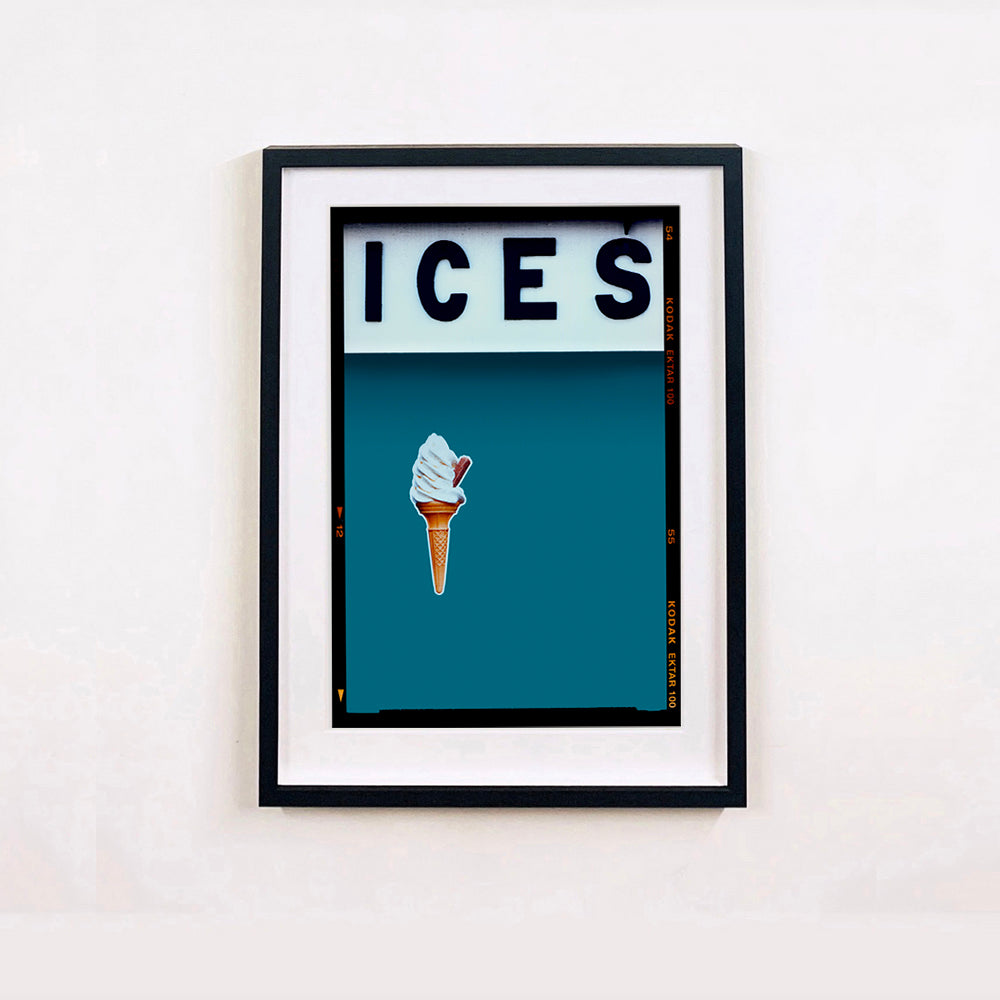 Black framed photograph by Richard Heeps.  At the top black letters spell out ICES and below is depicted a 99 icecream cone sitting left of centre against a blue teal coloured background.  