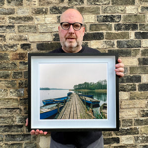 Richard Heeps holding Ormesby Little Broad Norfolk waterscape photograph framed in black.