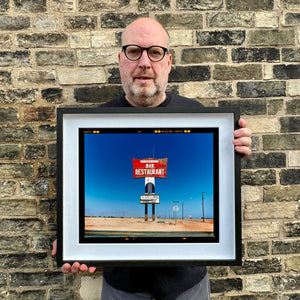 Richard Heeps holding Sundowner Landscape Salton Sea California photograph framed in black.