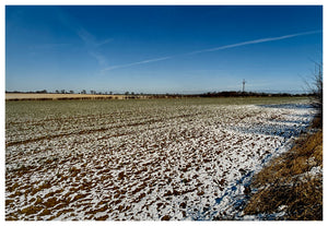 Photograph by Richard Heeps.  A snow covered field with a fast blue sky.