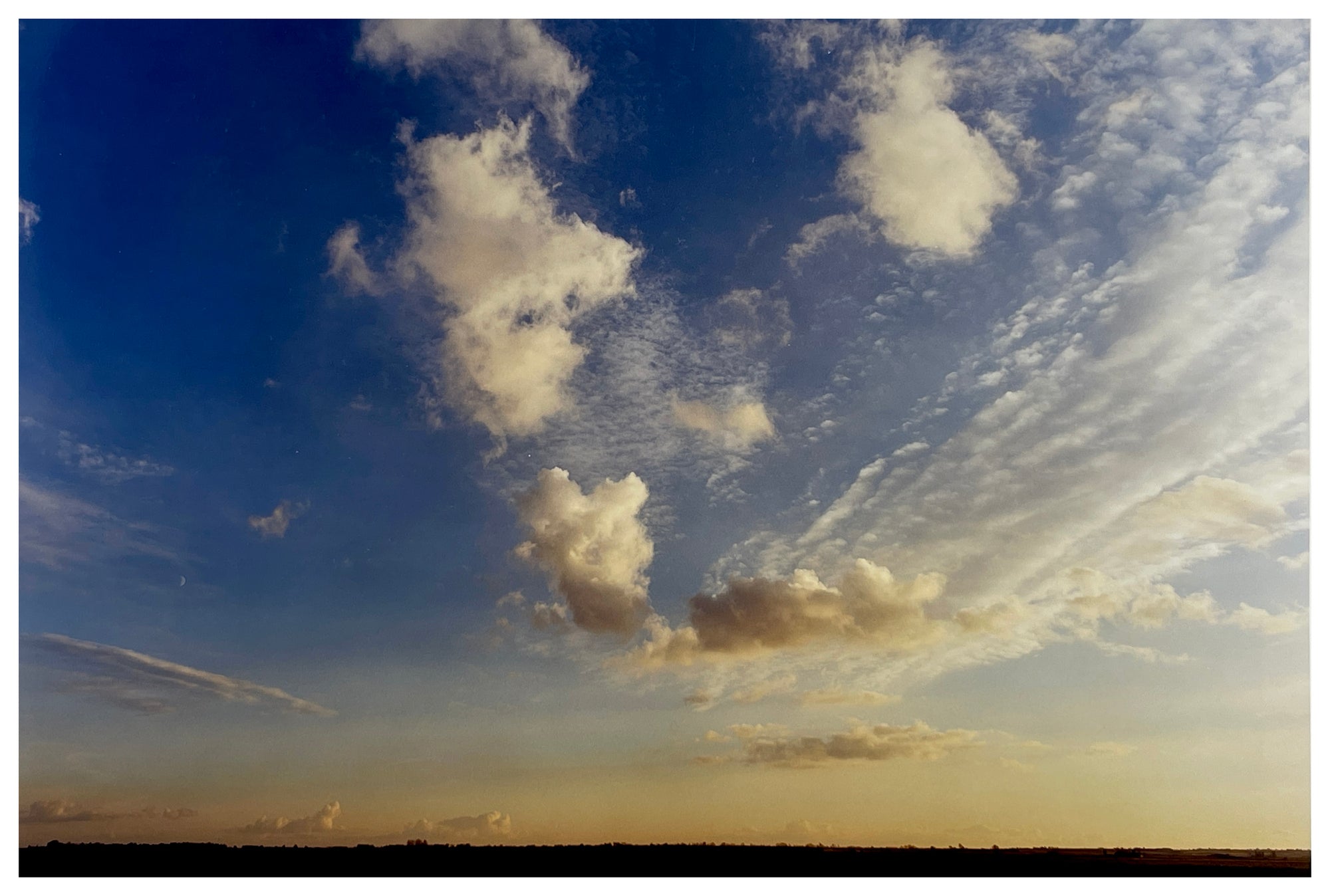 Photograph by Richard Heeps.  Clouds sit in a blue fen sky.