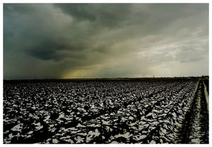 Photograph by Richard Heeps.  A snow covered, deeply trenched, peat fields sits below a thick cloud which is bringing in a storm.