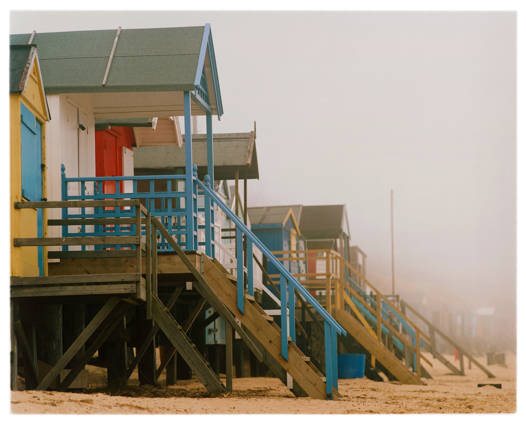 'Beach Huts', photographed by Richard Heeps in one of his favourite areas of the UK, the port town of Wells-next-the-sea, Norfolk. This piece captures the classic quintessential beach hut on an atmospherically foggy day.