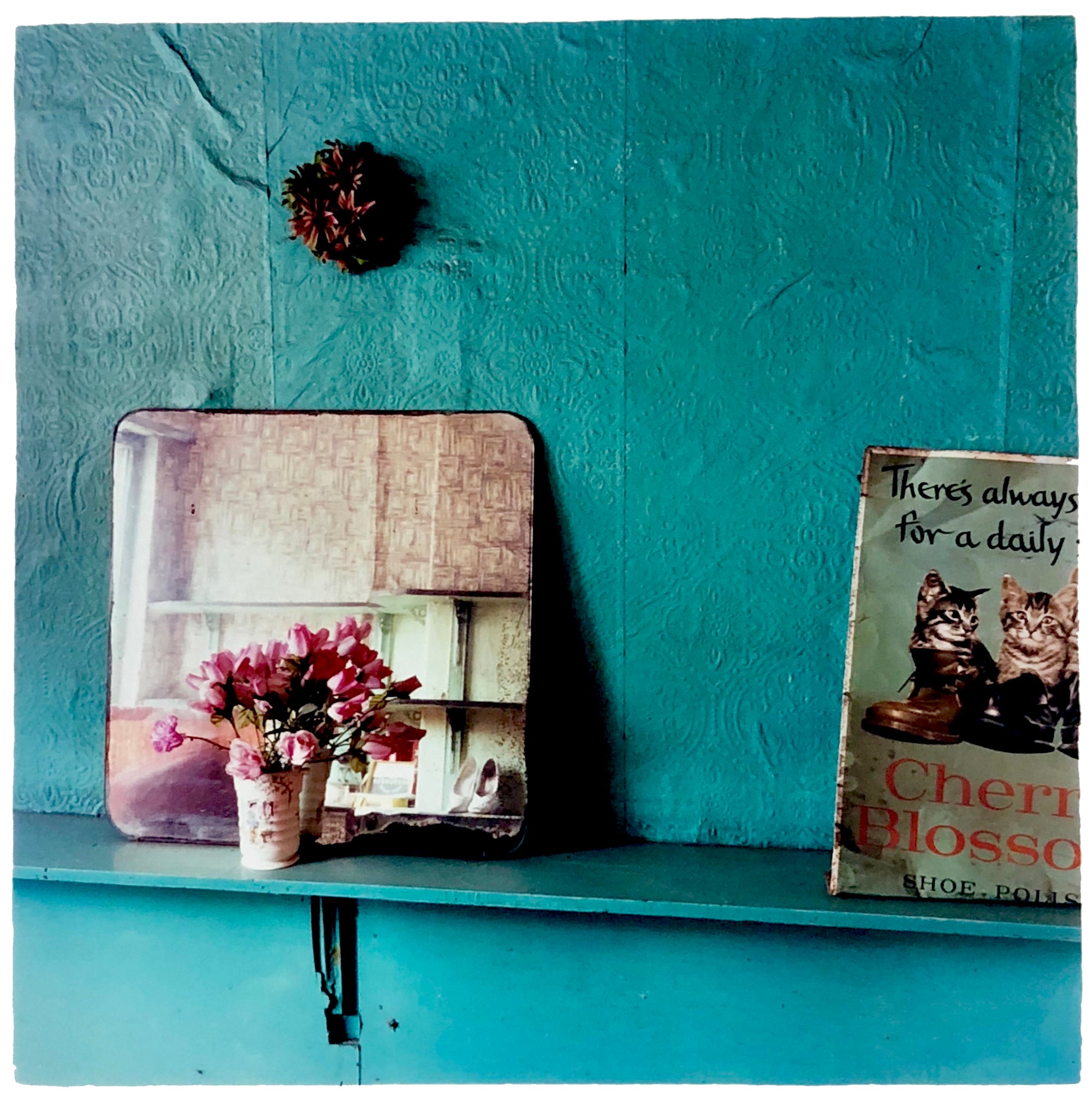 Vintage turquoise interior with flowers, a mirror and a book with cats on the front cover.
