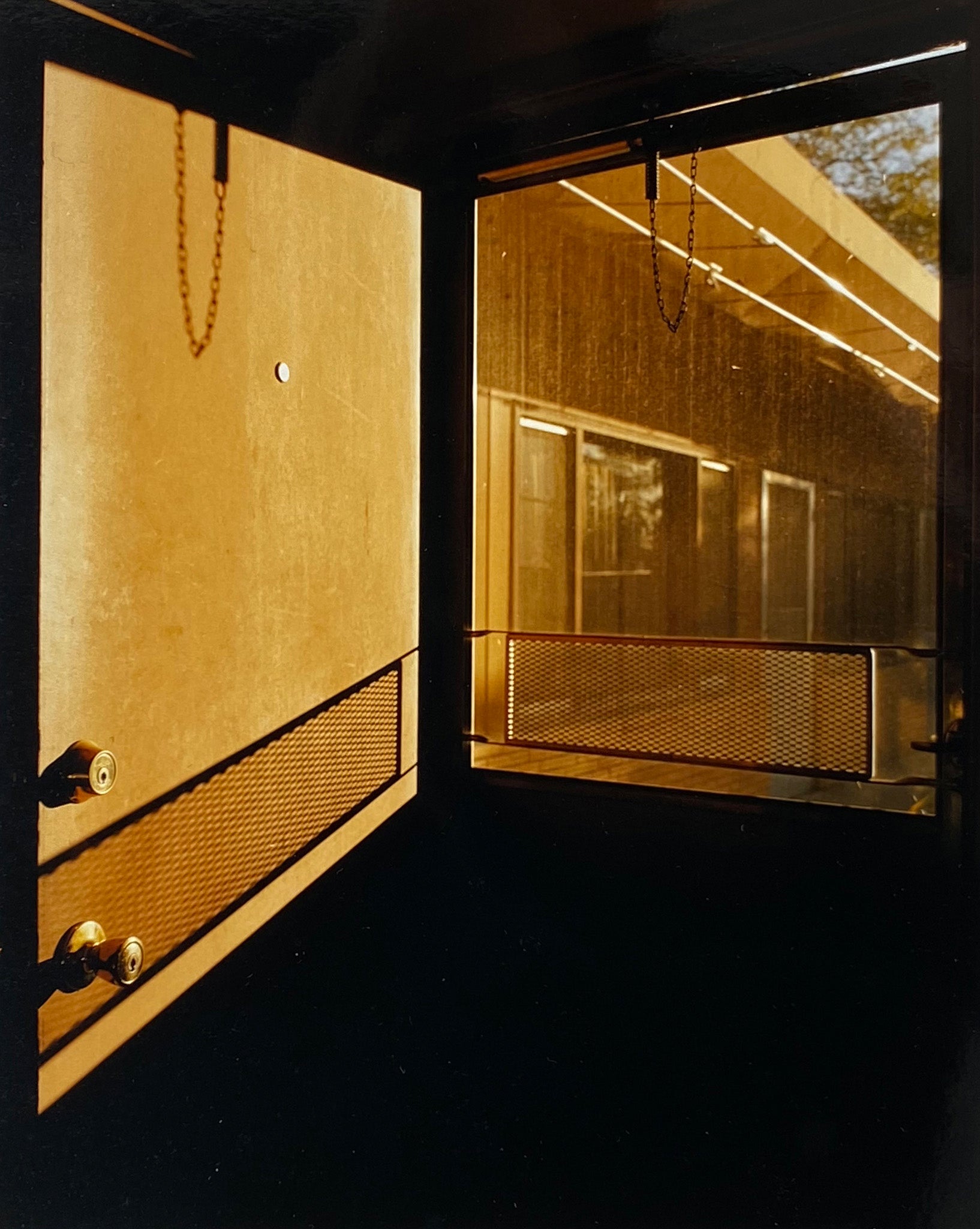 'Door - Lariat Motel' is a cinematic scene showing a doorway in the glowing evening light, with the setting sun casting shadows across the architecture. Richard Heeps photographed this artwork in Fallon, Nevada whilst on an American road trip. This artwork is part of Richard's 'Dream in Colour' series. 