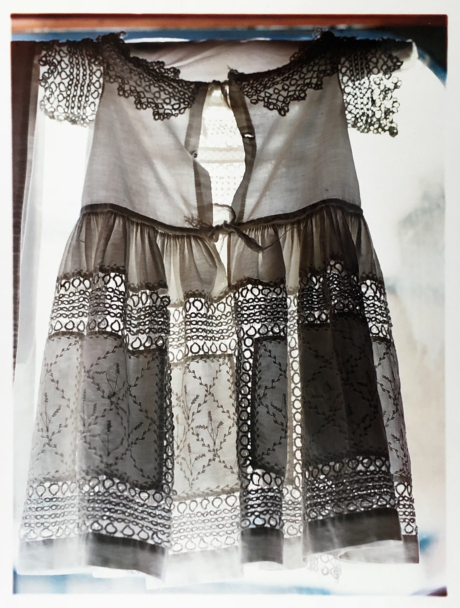 'Dress', a vintage white dress with the details of the lace backlit as it hangs over a window. Part of his Forward to the Past series documenting Preston Hall Museum in Stockton-on-Tees.