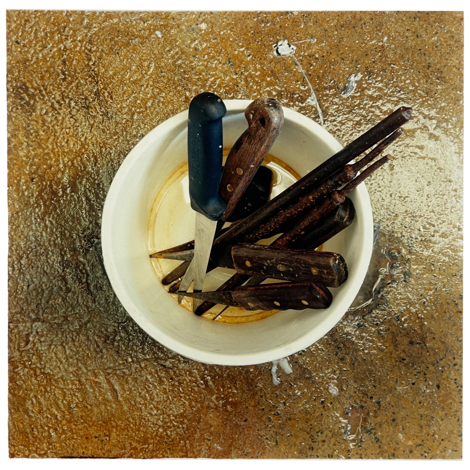 Photograph by Richard Heeps. A pot of filleters knives sits in the middle of a brown-mottled glass work surface.