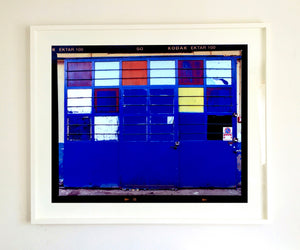 A blue, red and yellow hand painted garage door on the streets of Milan. Affordable fine art limited edition photographic prints, handmade in Richard’s Cambridge darkrooms.