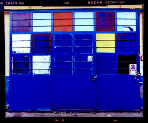 A blue, red and yellow hand painted garage door on the streets of Milan. Affordable fine art limited edition photographic prints, handmade in Richard’s Cambridge darkrooms.