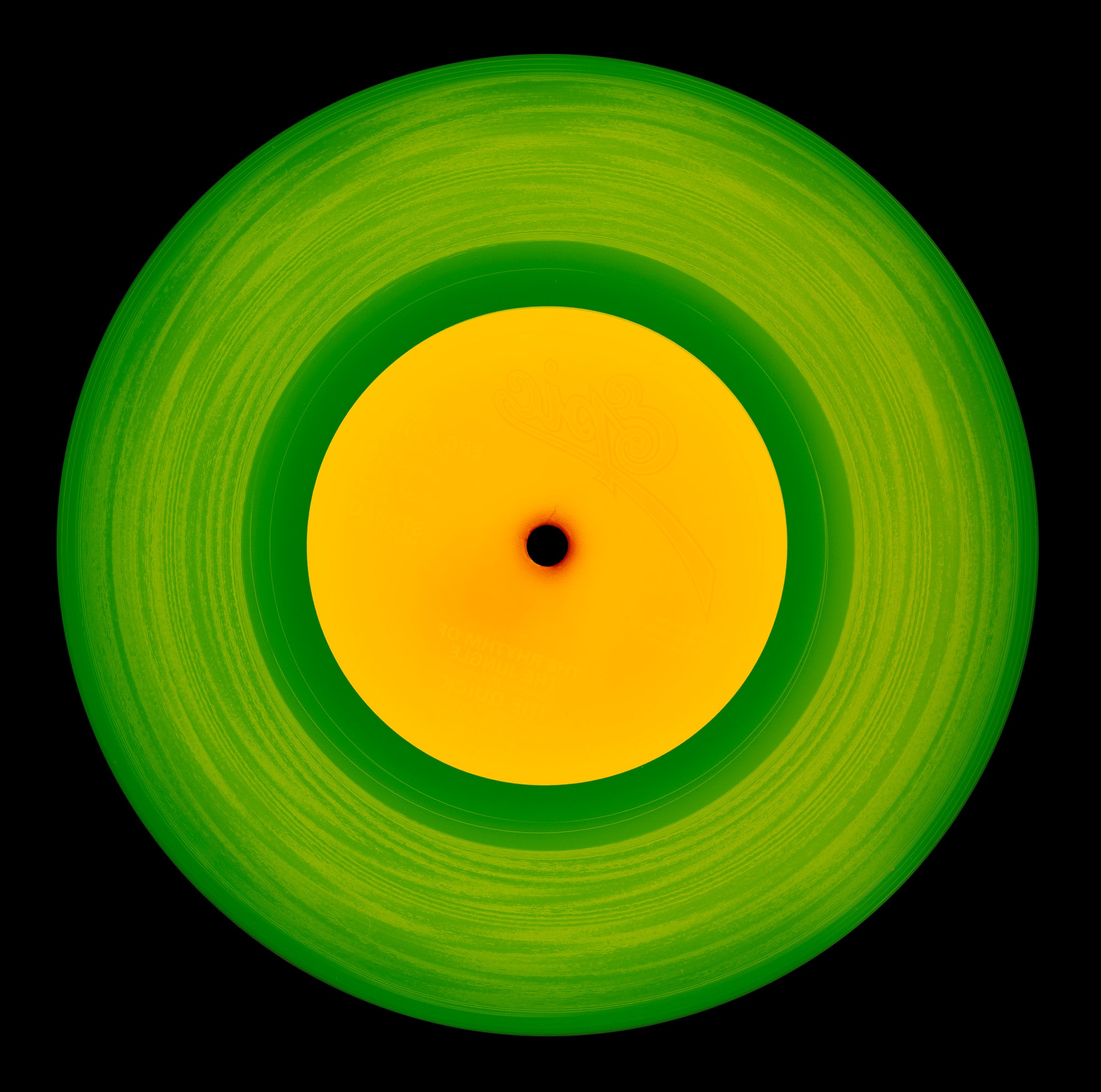 Photograph by Natasha Heidler and Richard Heeps.  A green vinyl record with circular grooves is central with an orange centre sitting on a black background.