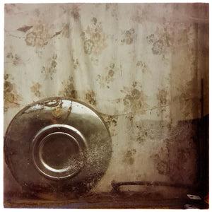 Photograph by Richard Heeps. A hub cap sits in the corner, behind it is a faded brown patterned curtain