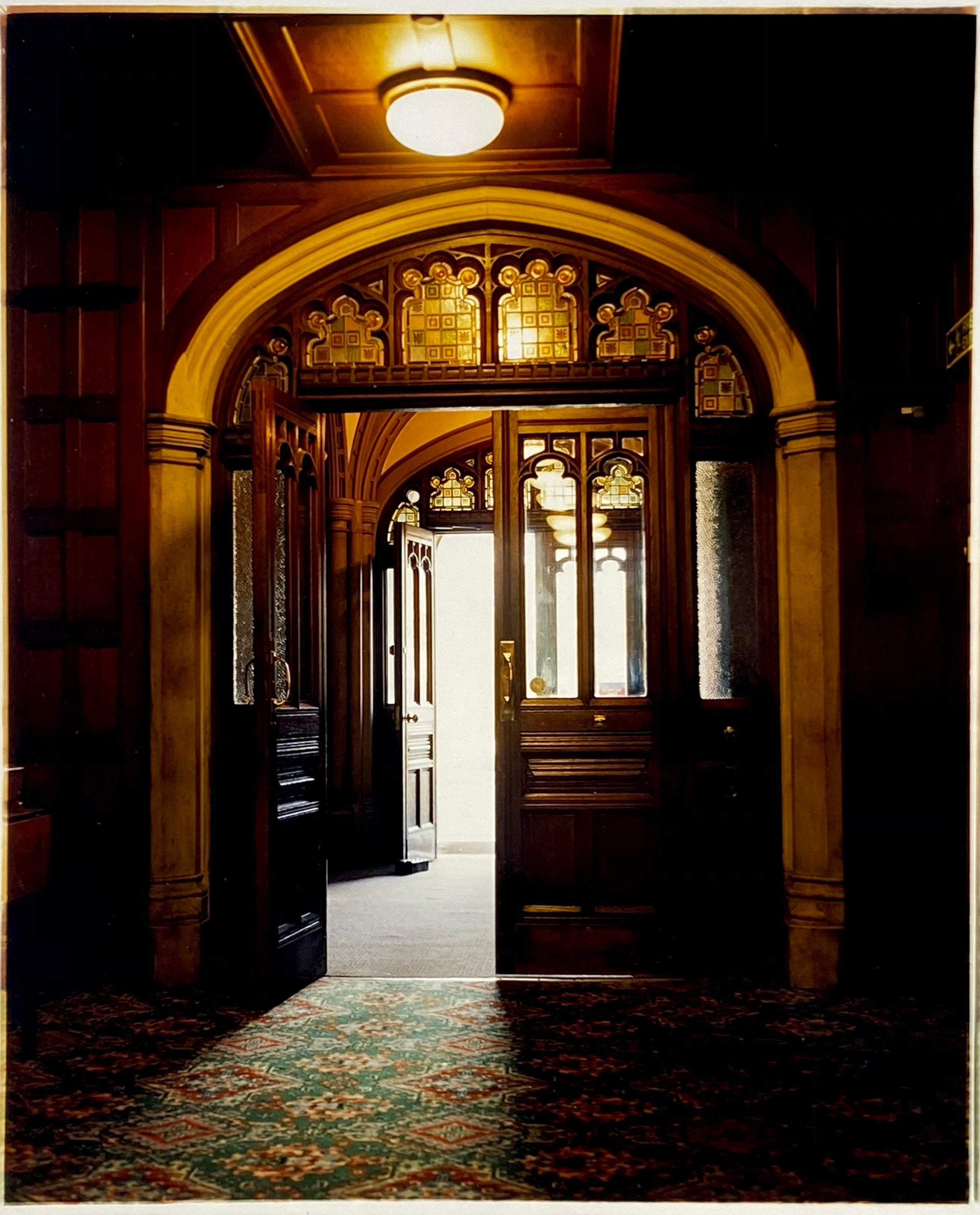 Bletchley Park entrance. Interior photography of a wooden panelled room with patterned carpet, stained glass and a warm light.