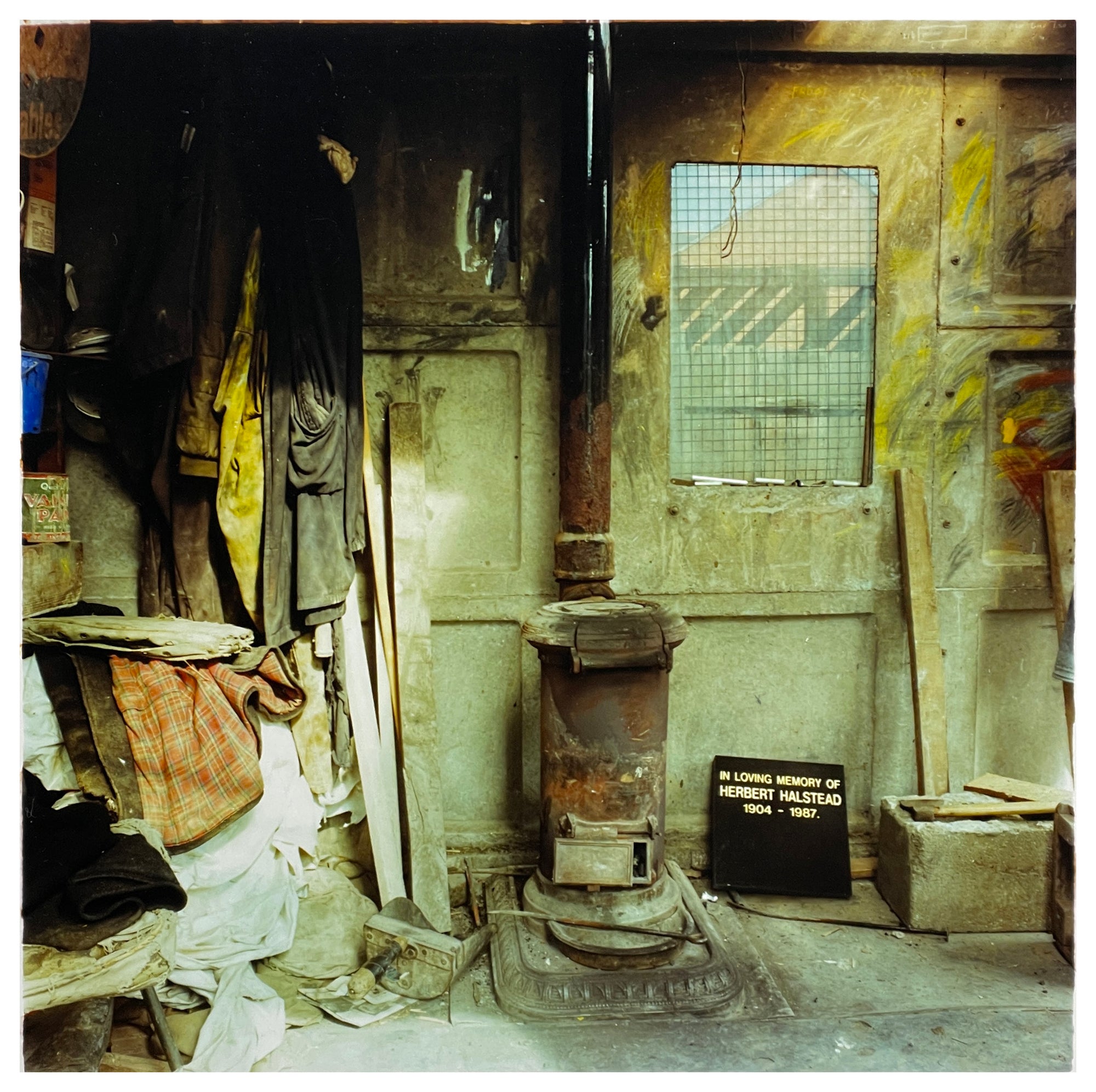 Photography by Richard Heeps.  Set in a workshop, the central piece is an old log burner.  Sitting on its right hand side is a grave stone in memory of Herbert Halstead.