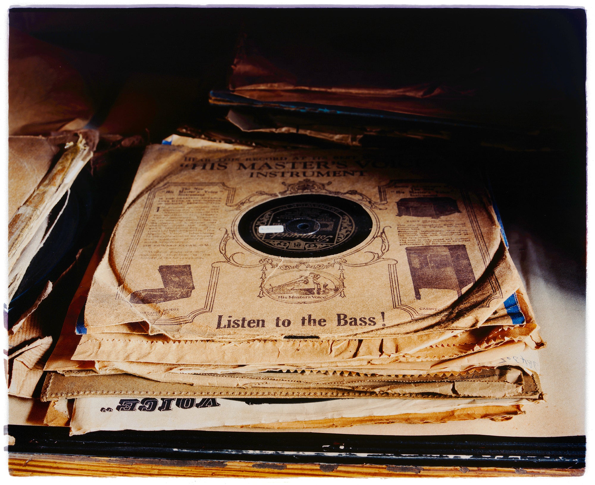 A vintage vinyl record collection in a pile, on the top is His Masters Voice, Listen to the Bass, photograph by Richard Heeps.