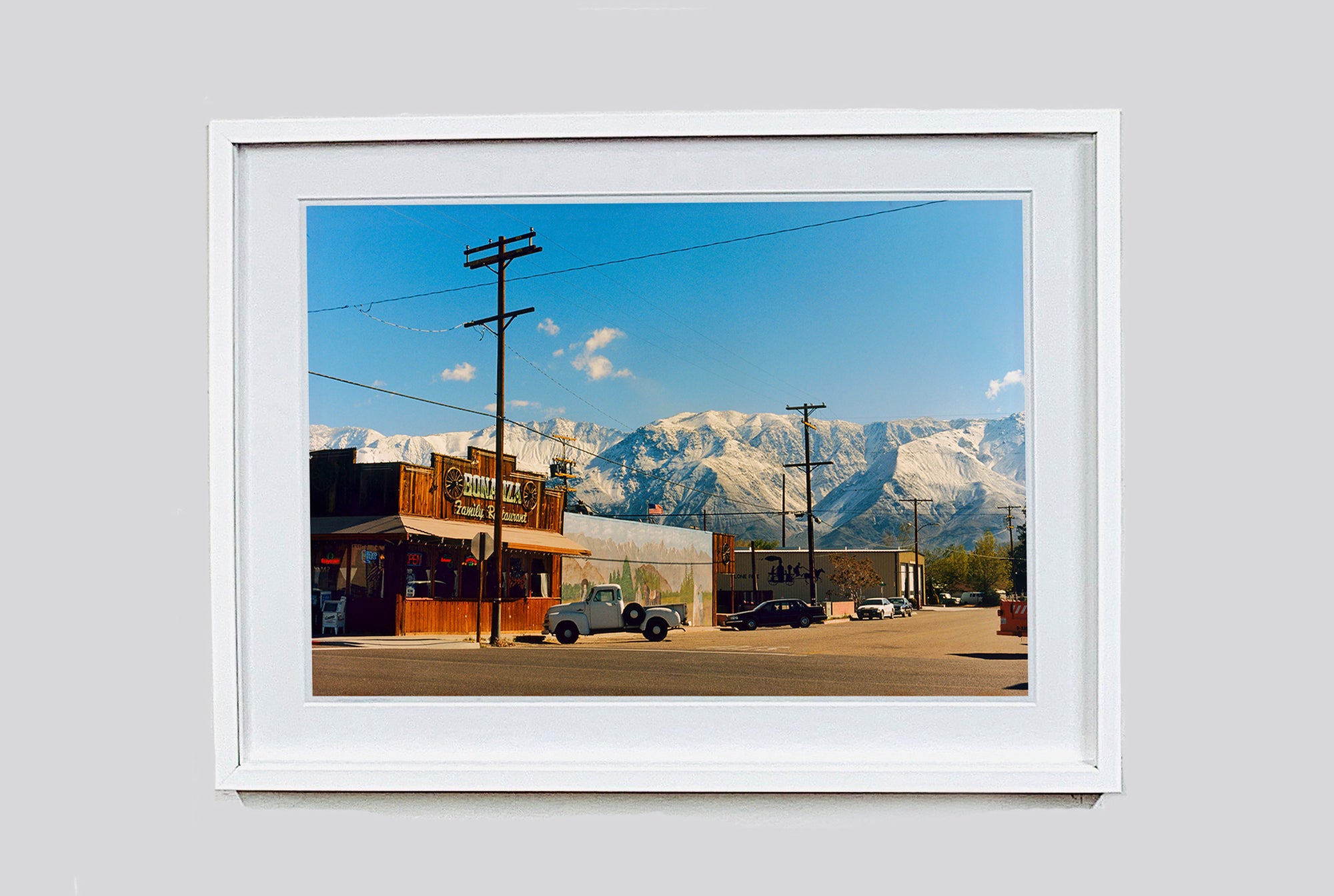 There is a cinematic style to this artwork, 'Lone Pine', taken in a former movie town in California where many Western films were made. Taken outside Richard's iconic interior photograph 'Bonanza Café', set in the Owens Valley against a mountainous  backdrop.