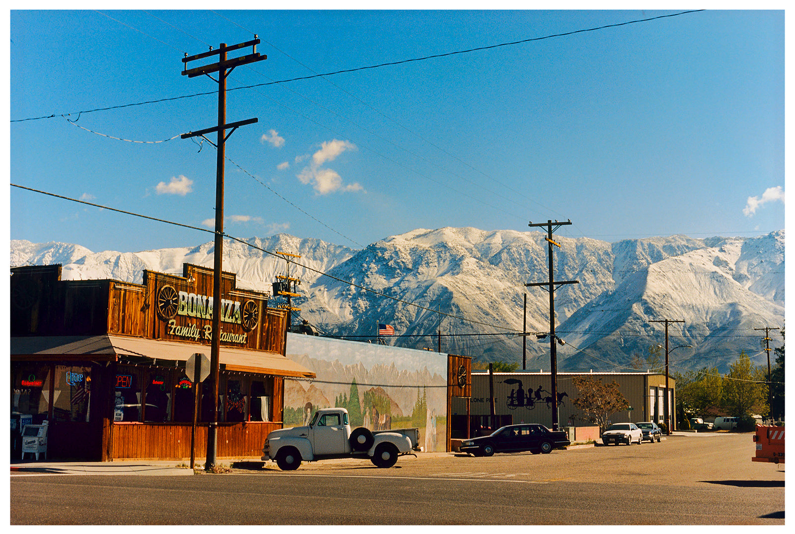There is a cinematic style to this artwork, 'Lone Pine', taken in a former movie town in California where many Western films were made. Taken outside Richard's iconic interior photograph 'Bonanza Café', set in the Owens Valley against a mountainous  backdrop.