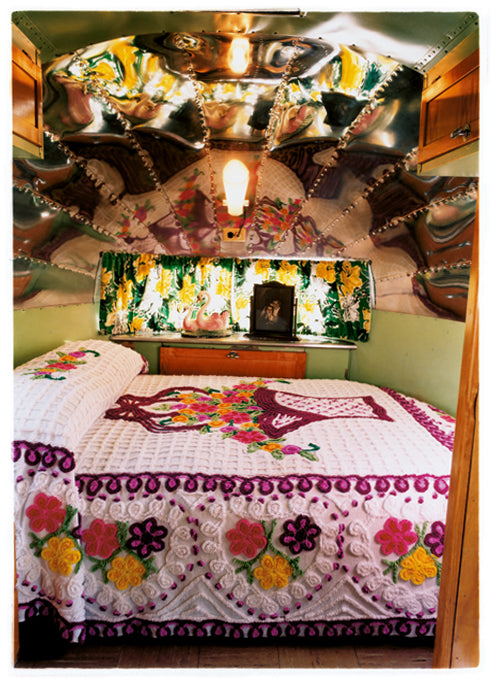 Interior photography with a mirrored ceiling and a neatly made bed in a American trailer.