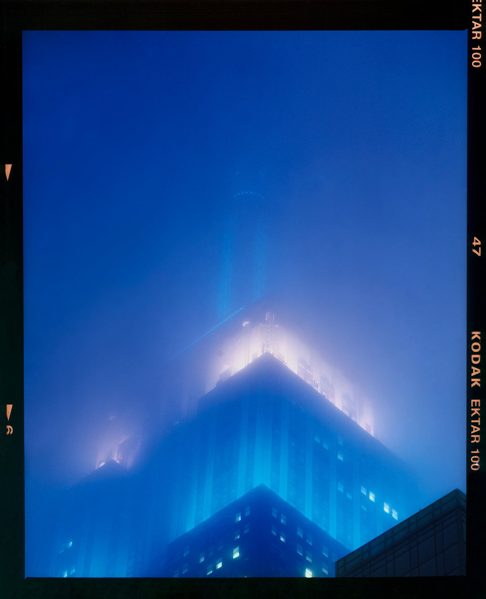 'NOMAD II (Film Rebate)', New York. Richard Heeps has photographed the iconic Empire State building in the mist. The NOMAD sequence of photographs capture the art deco architecture illuminated by changing colours, and is part of Richard's street photography portfolio which depict the colour, fabric and structure of cities with distinct style. This 6x7 format edition is bordered by the Kodak film rebate. 