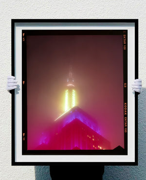 NOMAD, New York, photography by Richard Heeps capturing the iconic Empire State building in the mist. Part of a sequence of photographs capturing the art deco architecture illuminated in changing colours. This 6x7 format edition is bordered by the Kodak film rebate. This artwork is part of Richard's portfolio of street photography he is building up which depict the colour, fabric and structure of cities with distinct style