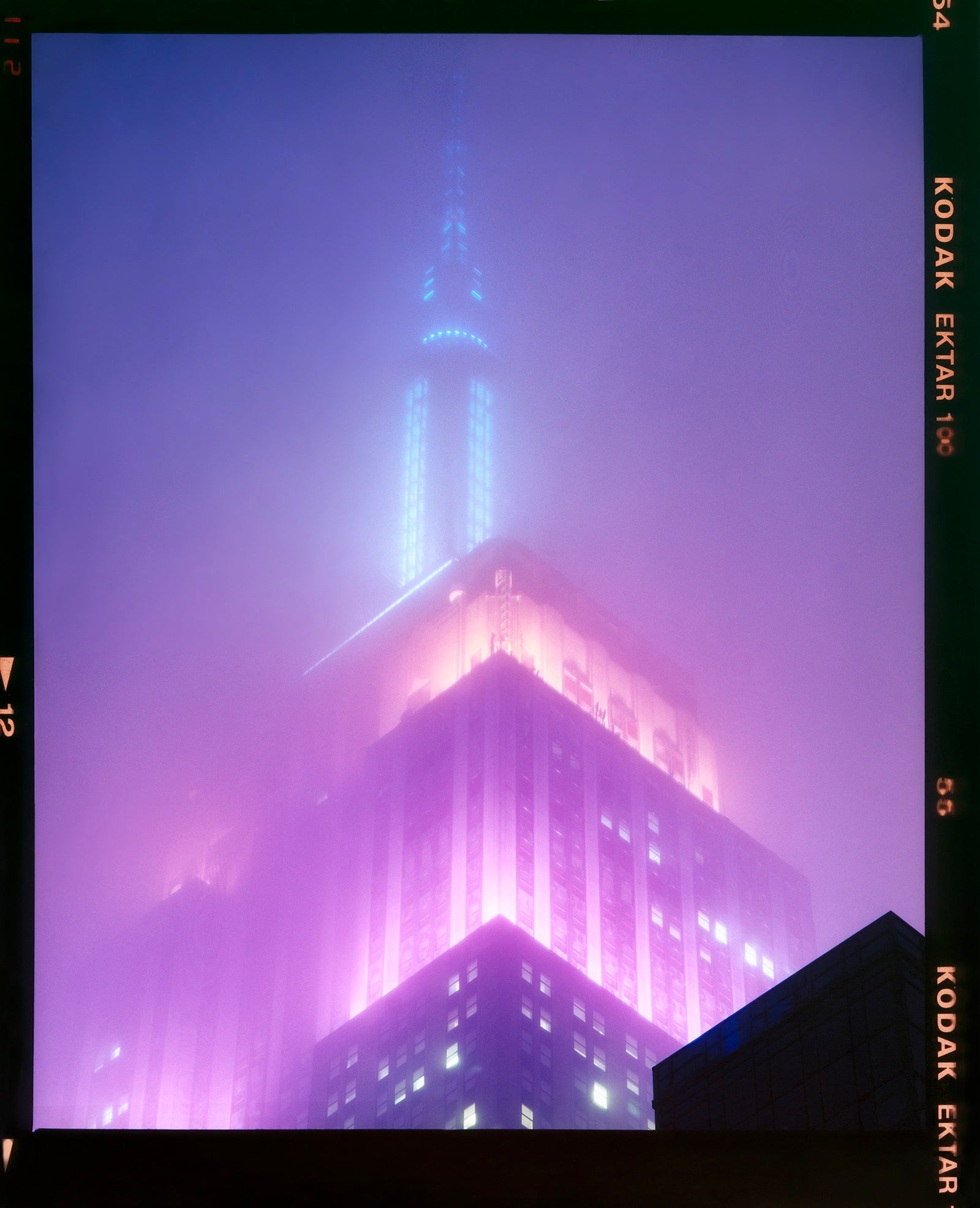 'NOMAD VIII (Film Rebate)', New York. Richard Heeps has photographed the iconic Empire State building in the mist. The NOMAD sequence of photographs capture the art deco architecture illuminated by changing colours, and is part of Richard's street photography portfolio which depict the colour, fabric and structure of cities with distinct style. This 6x7 format edition is bordered by the Kodak film rebate. 