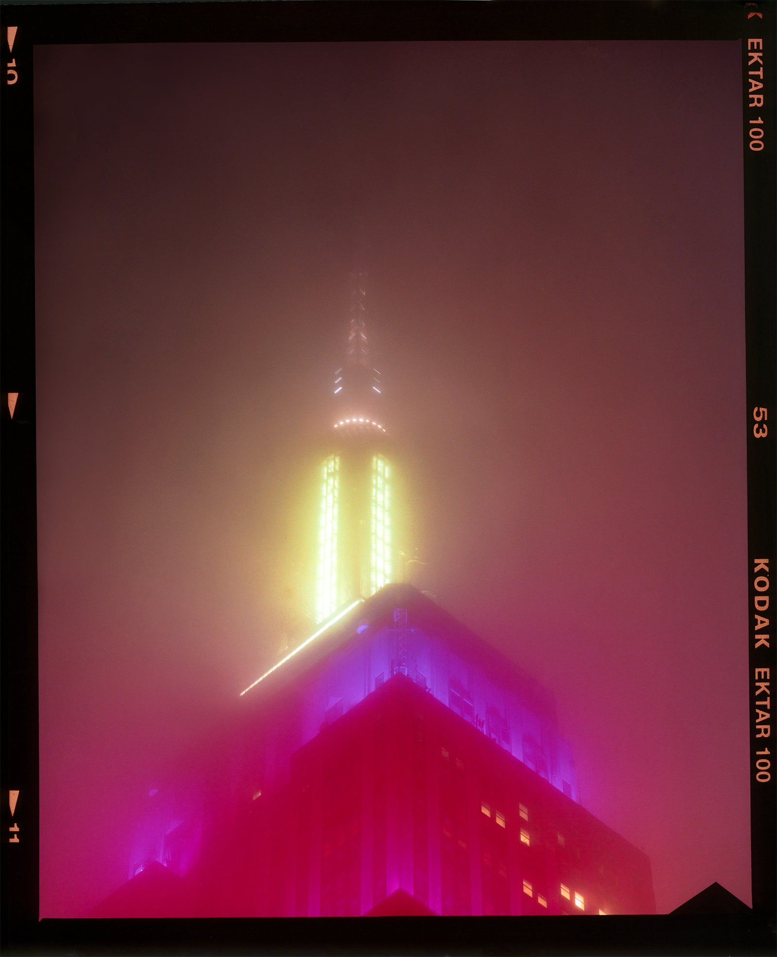 NOMAD, New York, photography by Richard Heeps capturing the iconic Empire State building in the mist. Part of a sequence of photographs capturing the art deco architecture illuminated in changing colours. This 6x7 format edition is bordered by the Kodak film rebate. This artwork is part of Richard's portfolio of street photography he is building up which depict the colour, fabric and structure of cities with distinct style