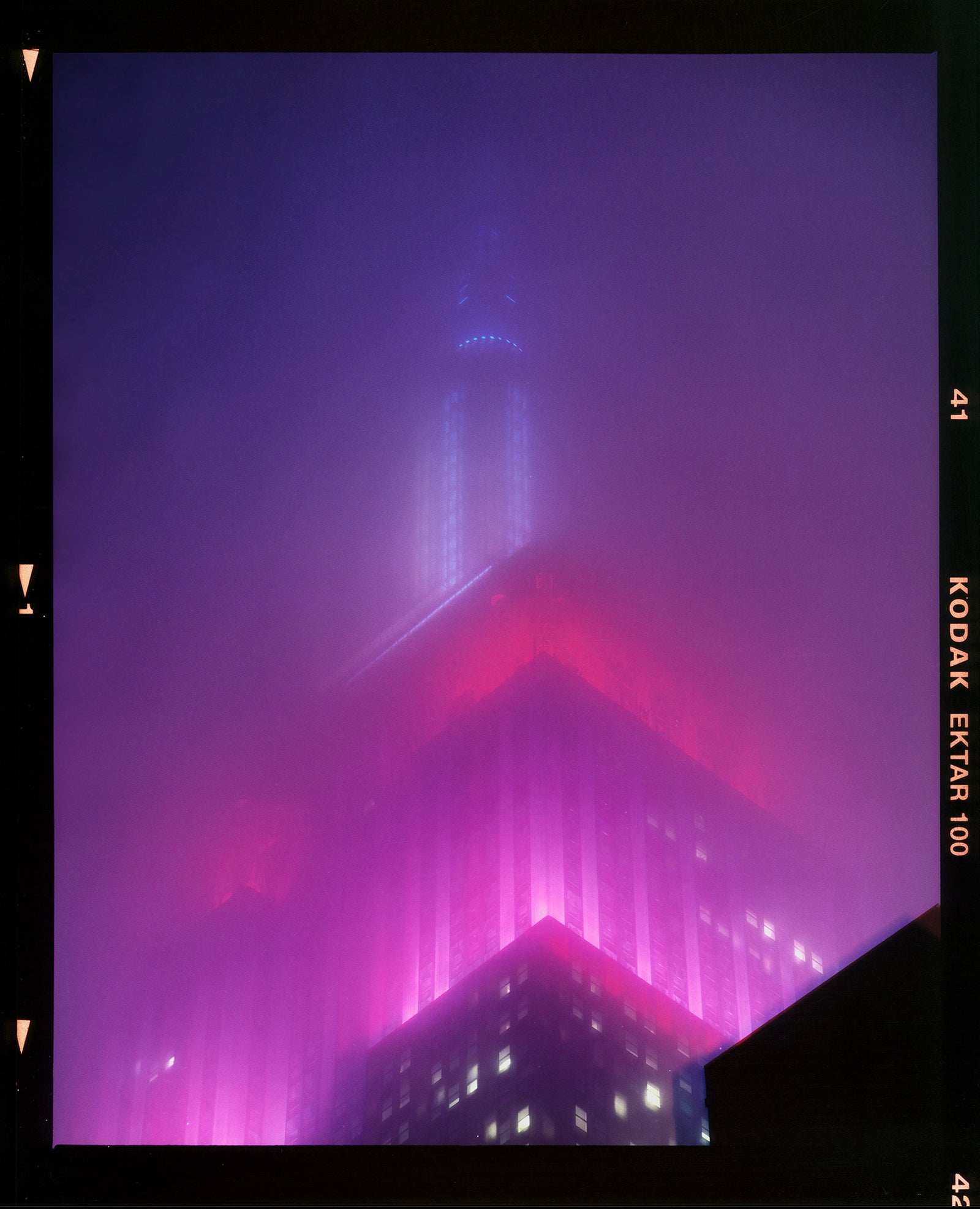 'NOMAD V (Film Rebate)', New York. Richard Heeps has photographed the iconic Empire State building in the mist. The NOMAD sequence of photographs capture the art deco architecture illuminated by changing colours, and is part of Richard's street photography portfolio which depict the colour, fabric and structure of cities with distinct style. This 6x7 format edition is bordered by the Kodak film rebate. 