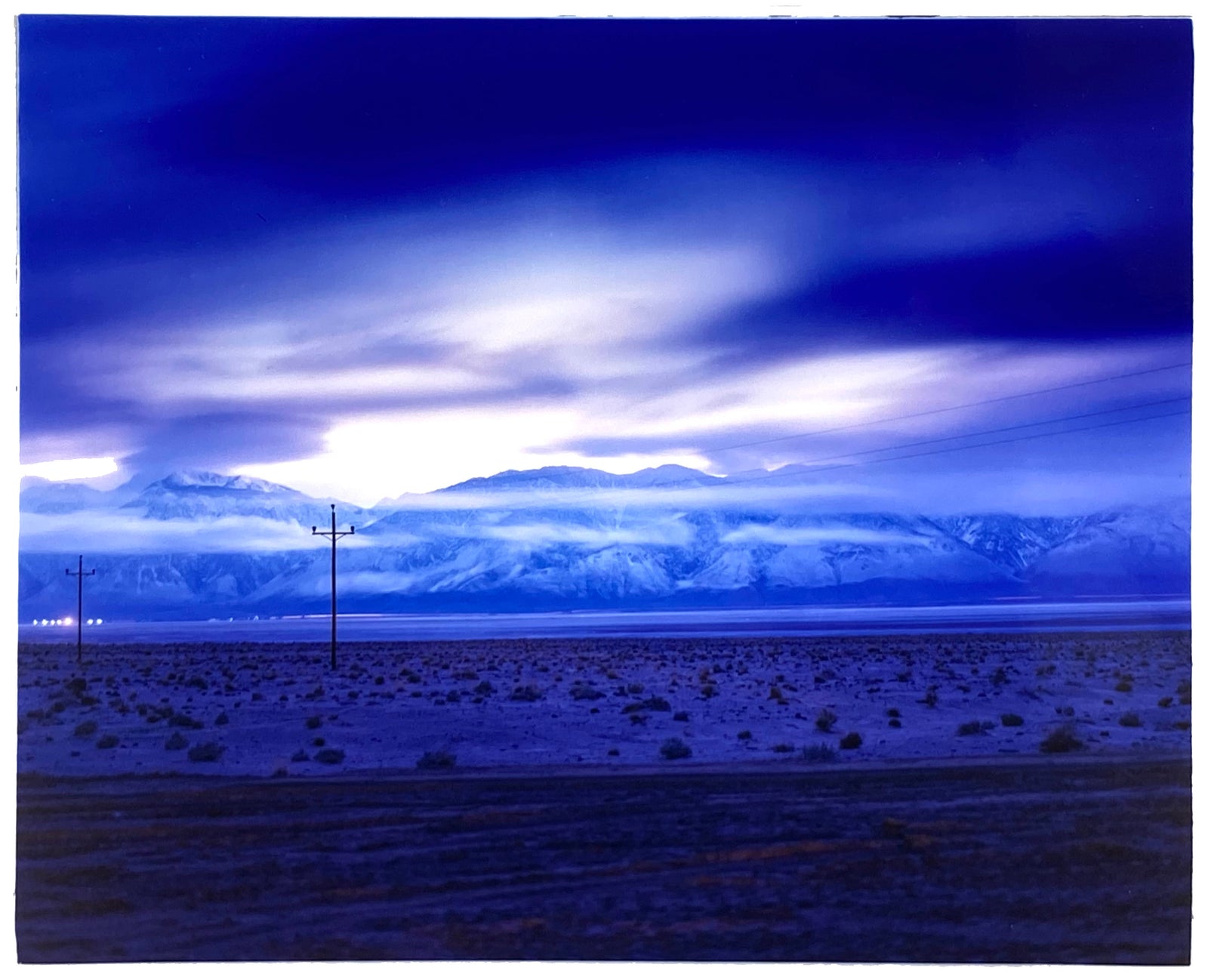 Photograph held by photographer Richard Heeps. A blue light hits vast land, mountains and a big sky.