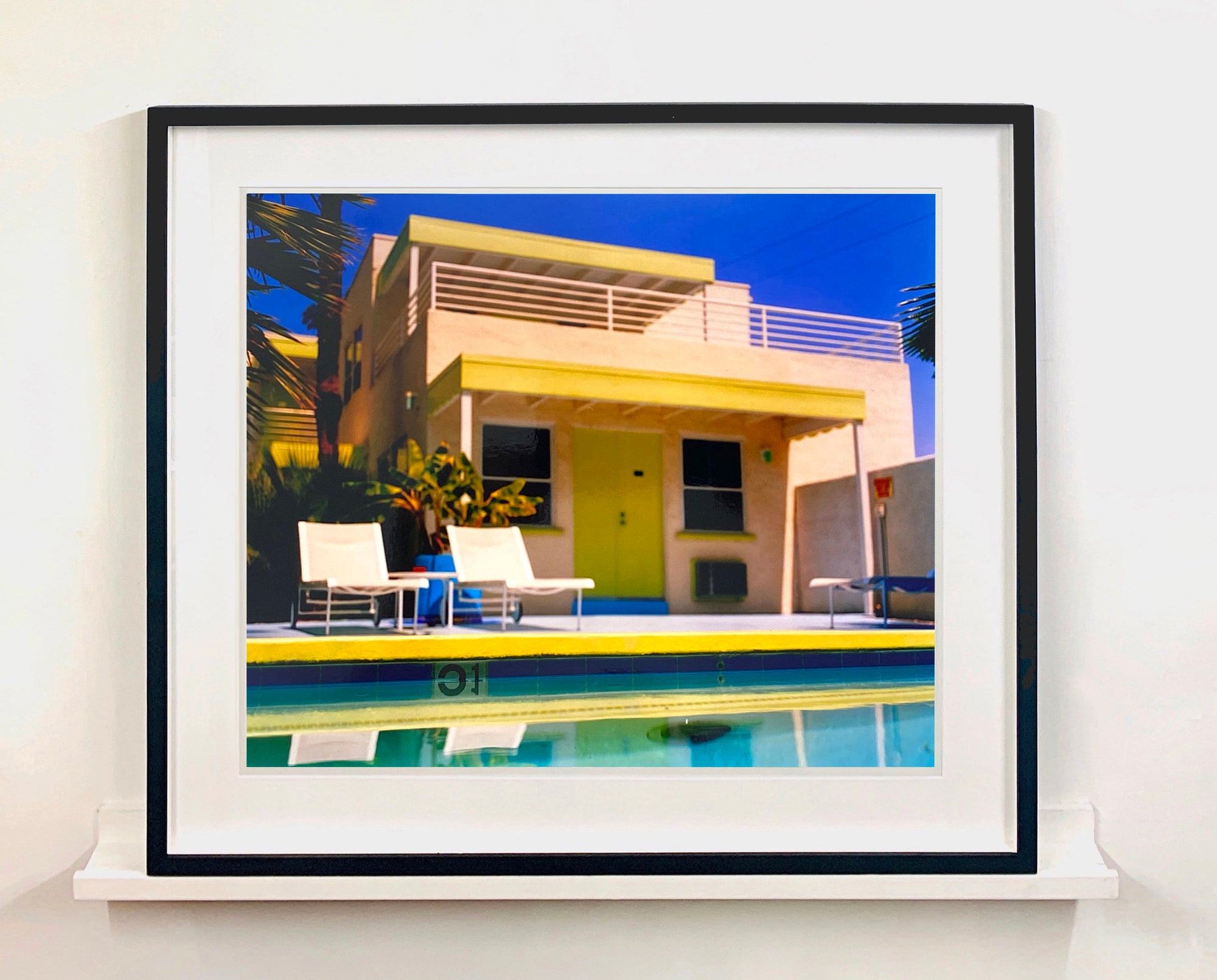 Palm Springs Poolside I, California, shows classic mid-century Palm Springs architecture, featuring cool blue skies and pool with accents of pink and almost neon yellow. 
