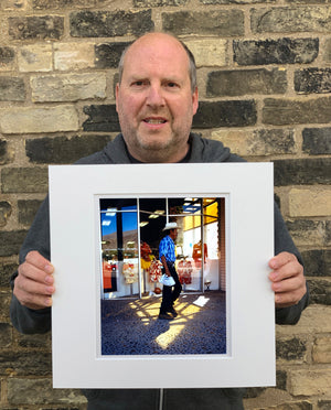 'Boutique' is street portrait, taken in Palm Springs, California. This piece is different from Richard Heeps' usual style, but everything fell into place: the light, the colours, and the man walking through the shot.