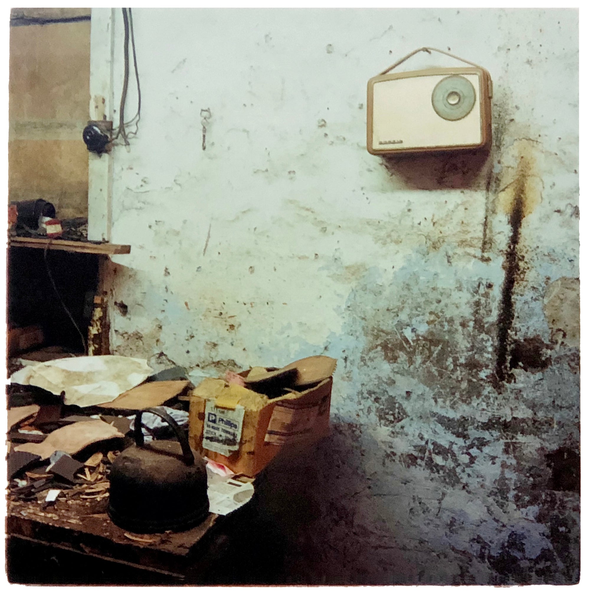 A vintage radio hangs on the wall in a dilapidated room.