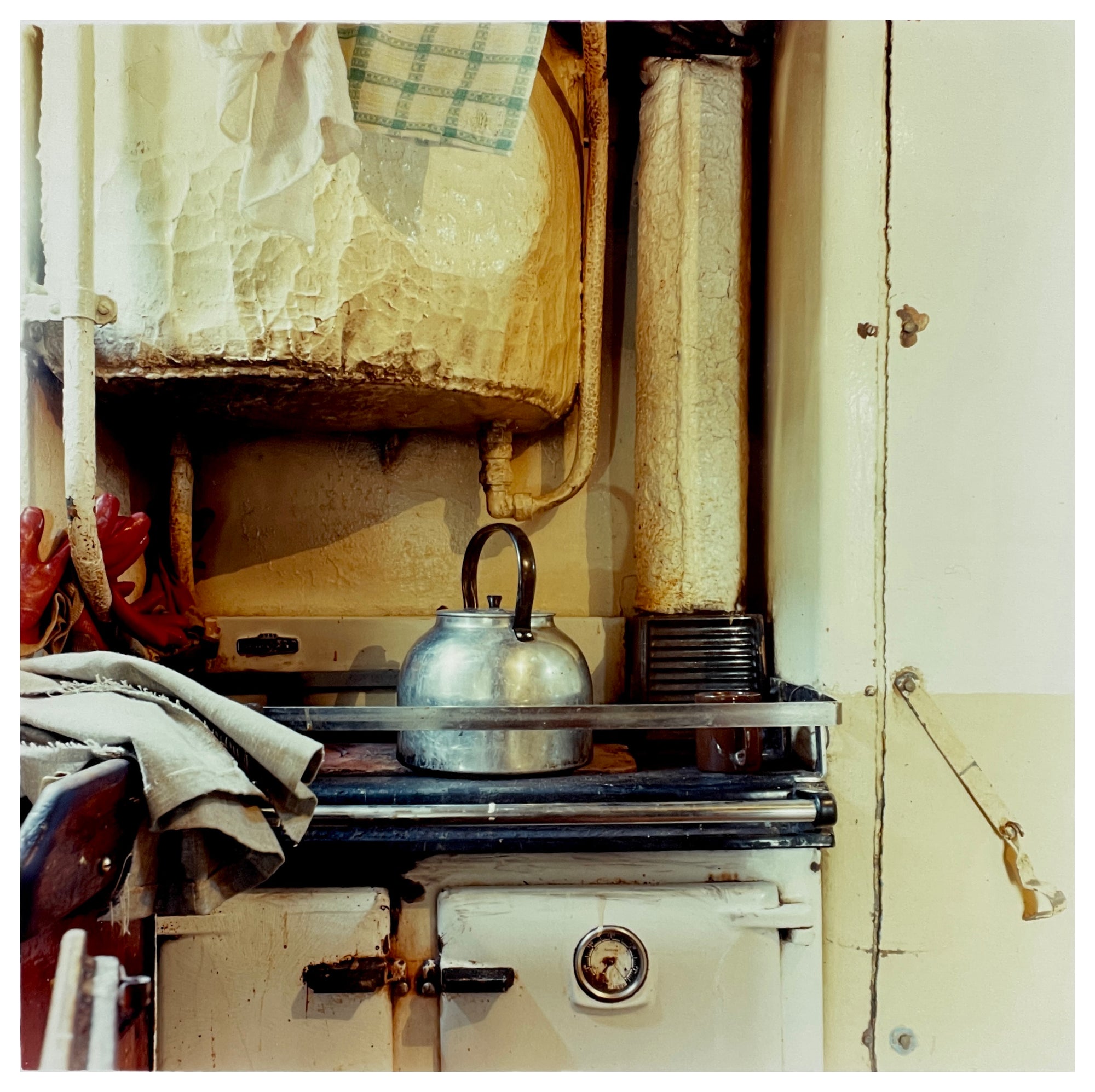 Photograph by Richard Heeps.  A well worn aga provides a home for a big steel kettle.  Above, is an old boiler.
