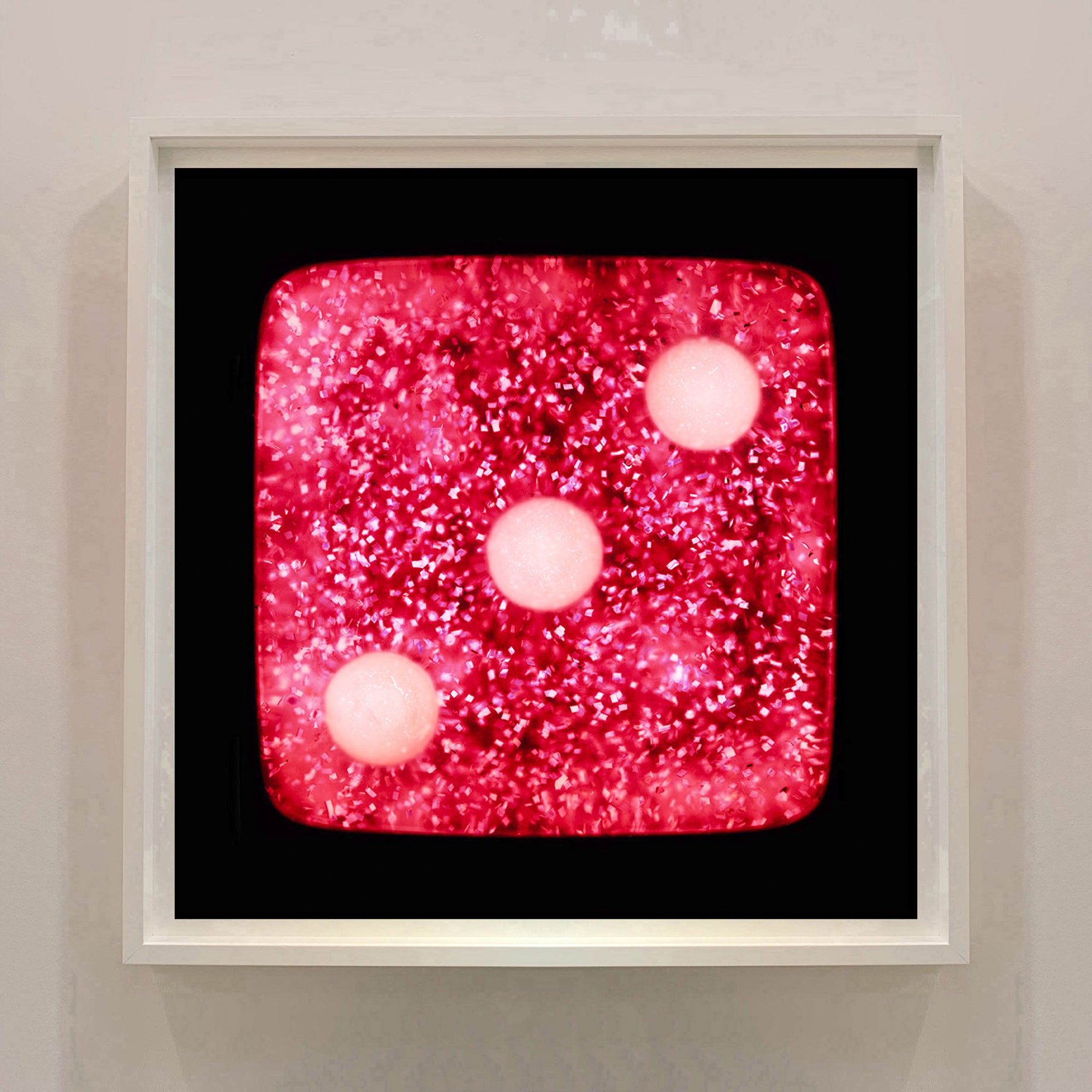 From Heidler & Heeps Dice Series, 'Raspberry Sparkles Three' is a glittery pink dice suspended on a black background, hypnotically curious in both content and technique, viewers find themselves pleasantly puzzled. Heidler & Heeps have developed their own dichromatic technique resulting in something, which is neither a straightforward photograph, nor photogram. 