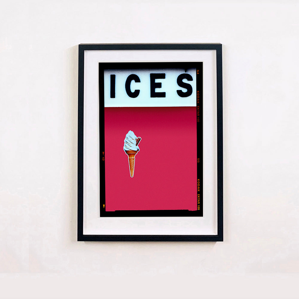 Black framed photograph by Richard Heeps.  At the top black letters spell out ICES and below is depicted a 99 icecream cone sitting left of centre against a raspberry coloured background.  