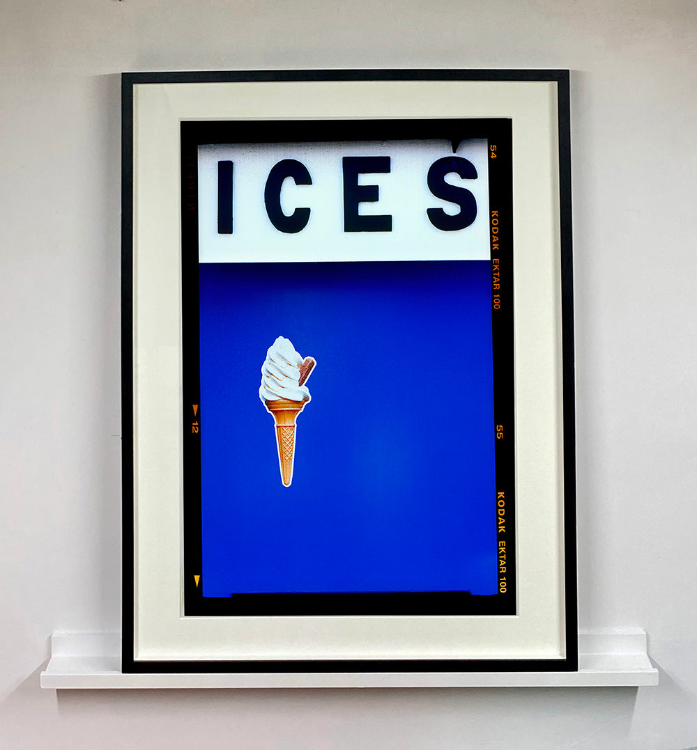 Photograph by Richard Heeps.  At the top black letters spell out ICES and below is depicted a 99 icecream cone sitting left of centre against a blue coloured background.  