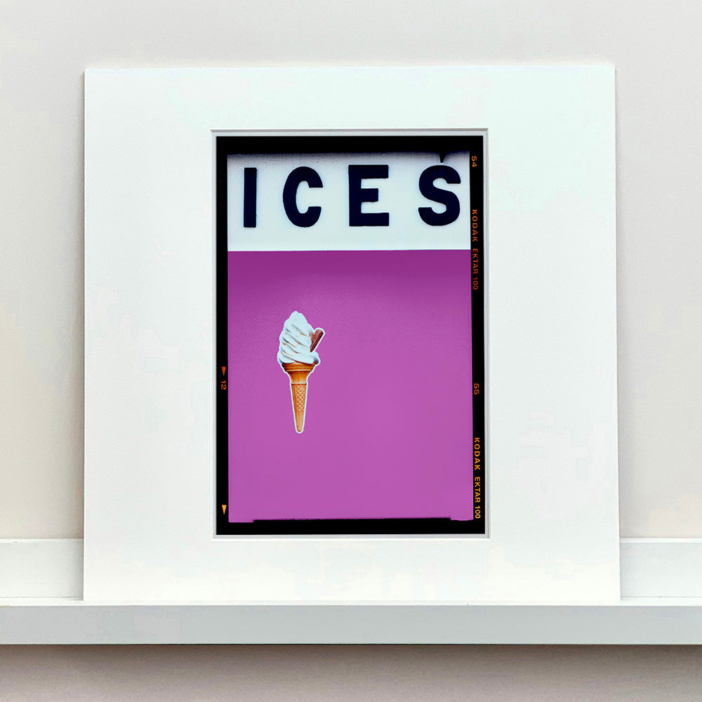 Photograph by Richard Heeps.  Black letters spell out ICES and below is depicted a 99 icecream cones sitting left of centre against a plum coloured background.  