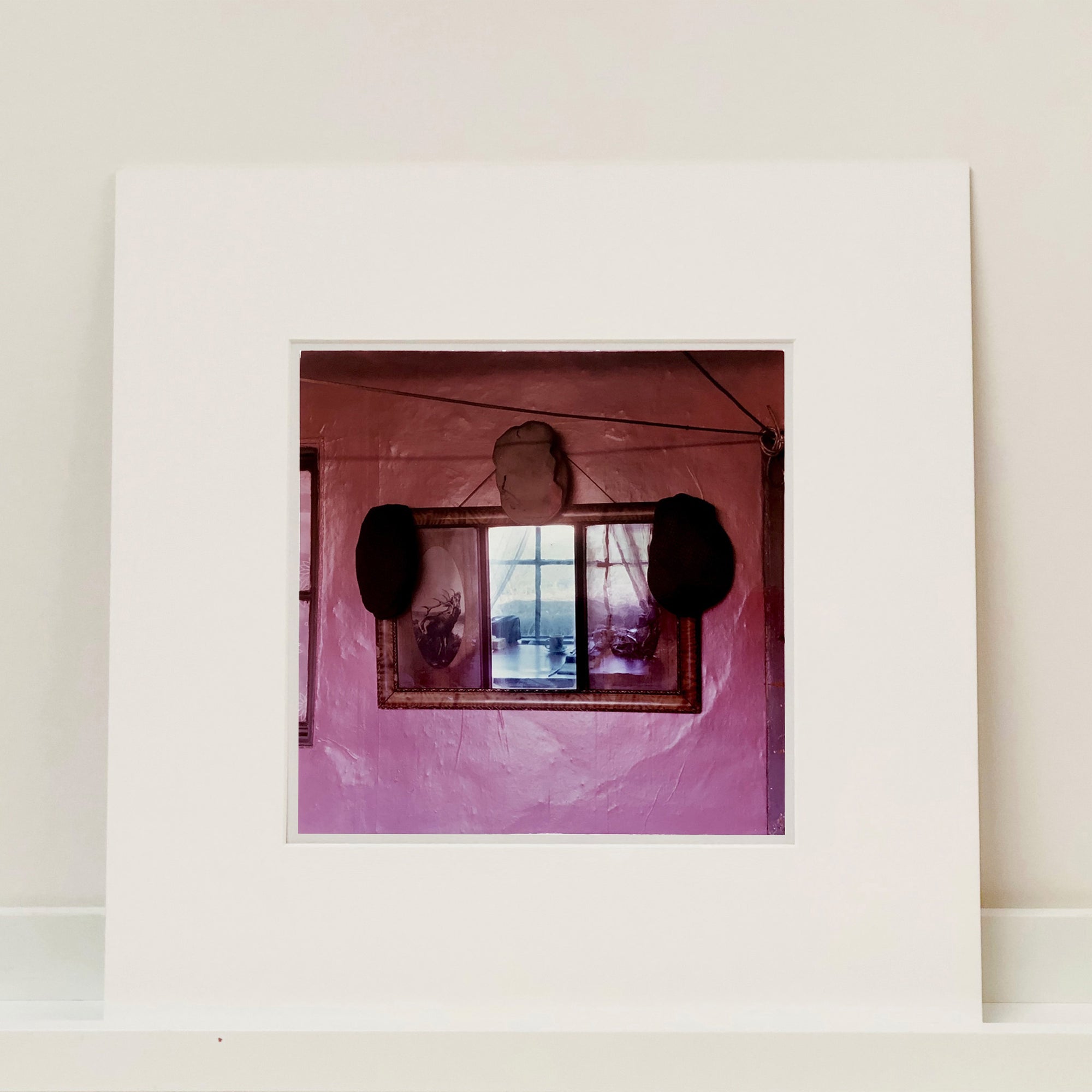Photograph by Richard Heeps. The fenland landscape reflects beyond the room in the mirror on the pink cottage wall adorned by three flat caps