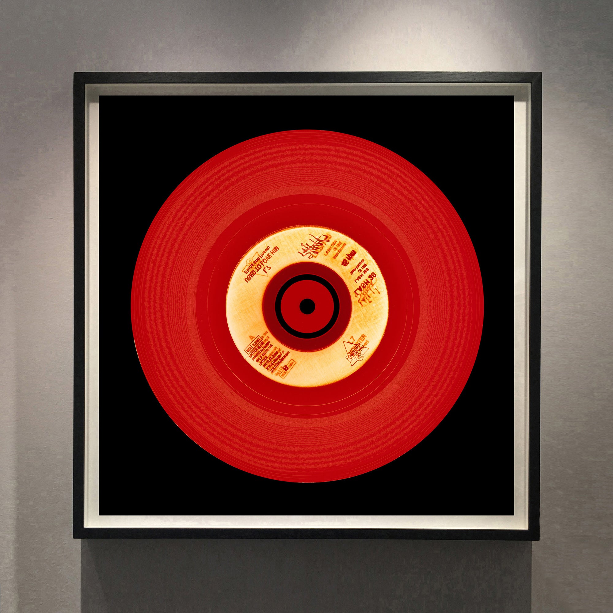 Photograph of a red vinyl record on a black background. Photographers Heidler and Heeps