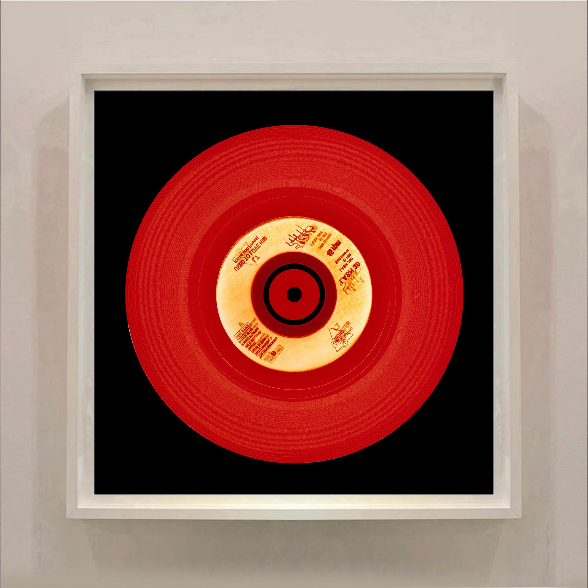 Photograph of a red vinyl record on a black background. Photographers Heidler and Heeps