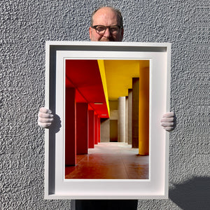 Monte Amiata housing, Gallaratese Quarter, Milan. Red and yellow brutalist architecture photograph by Richard Heeps framed in white.
