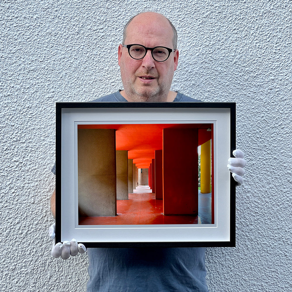 Red and yellow brutalist concrete architecture photograph by Richard Heeps framed in black.