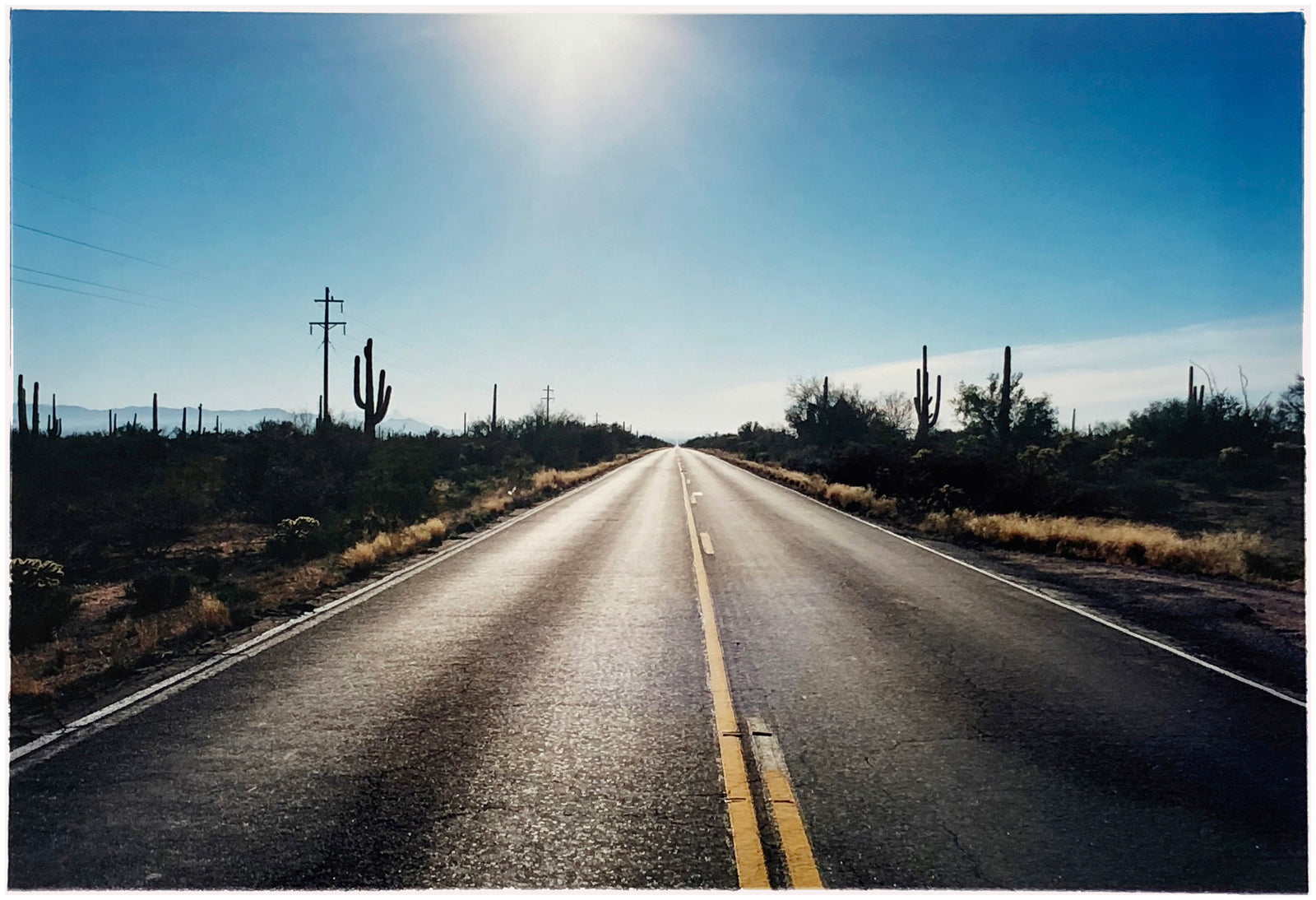 'Road to Gunsight' photographed on Highway 86, Arizona in 2001 is part of Richard Heeps' 'Dream in Colour' series. This classic American open road imagery appears throughout his work. 