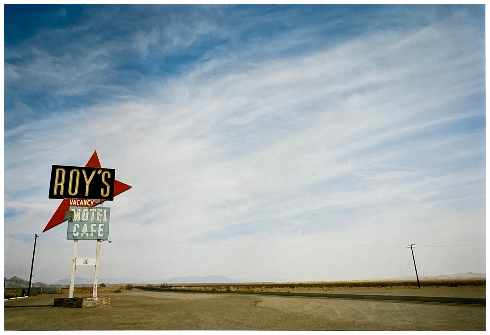 Part of the 'Dream in Colour' Series, 'Roy's - Route 66' is one of Richard Heeps' classic American sign artworks featuring the road sign for Roy's Motel, which demonstrates historic Mid-Century Modern Googie architecture. This photograph was capture on the National Trails Highway of U.S. Route 66, in the Mojave Desert town of Amboy in San Bernardino County, California. 