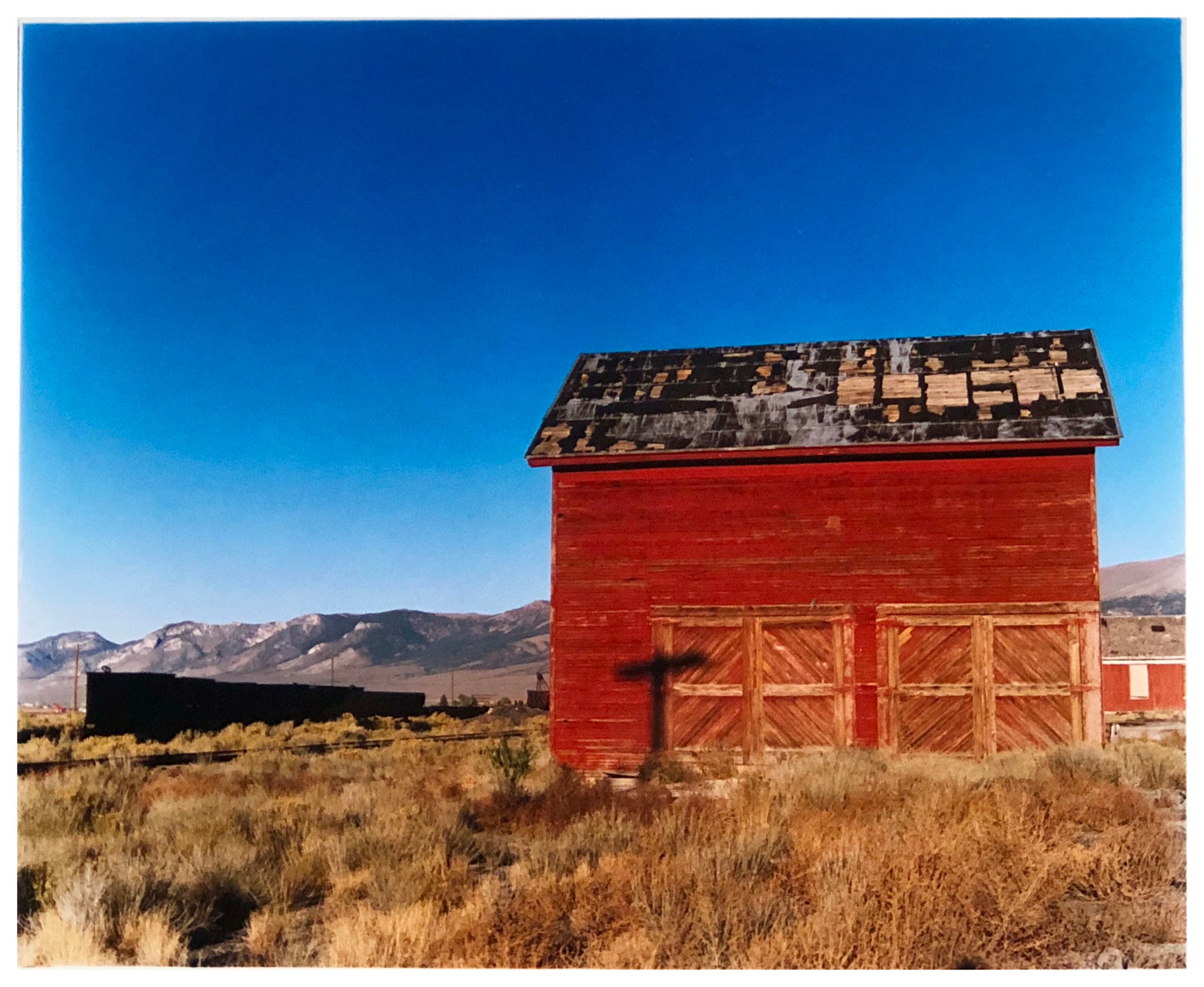 A red shed against a blue sky in a landscape photograph taken in Nevada on an American road trip by Richard Heeps.