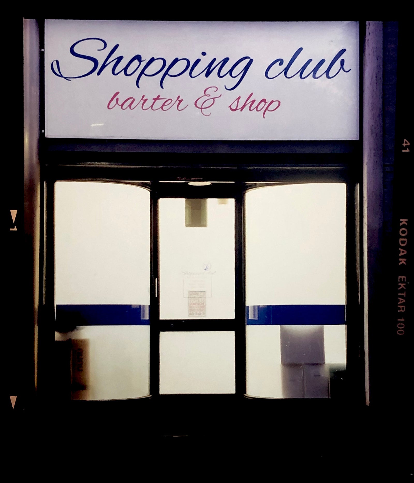 Shopping Club shows typography on a frosted glass window in Milan, Italy. 