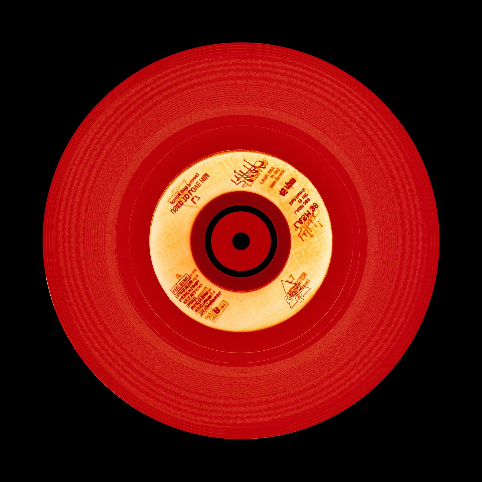Photograph of a red vinyl record on a black background.  Photographers Heidler and Heeps
