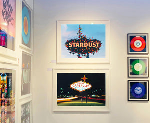 'Stardust', shows a sparkling roadside sign against a bright blue and slightly clouded sky. This artwork offers a classic Americana feel and incorporates elements of Googie style design. Richard Heeps beautifully captures parts of Las Vegas which are no longer there. This photograph was taken in 2001 but only made in Richard's darkroom for the first time in 2017.