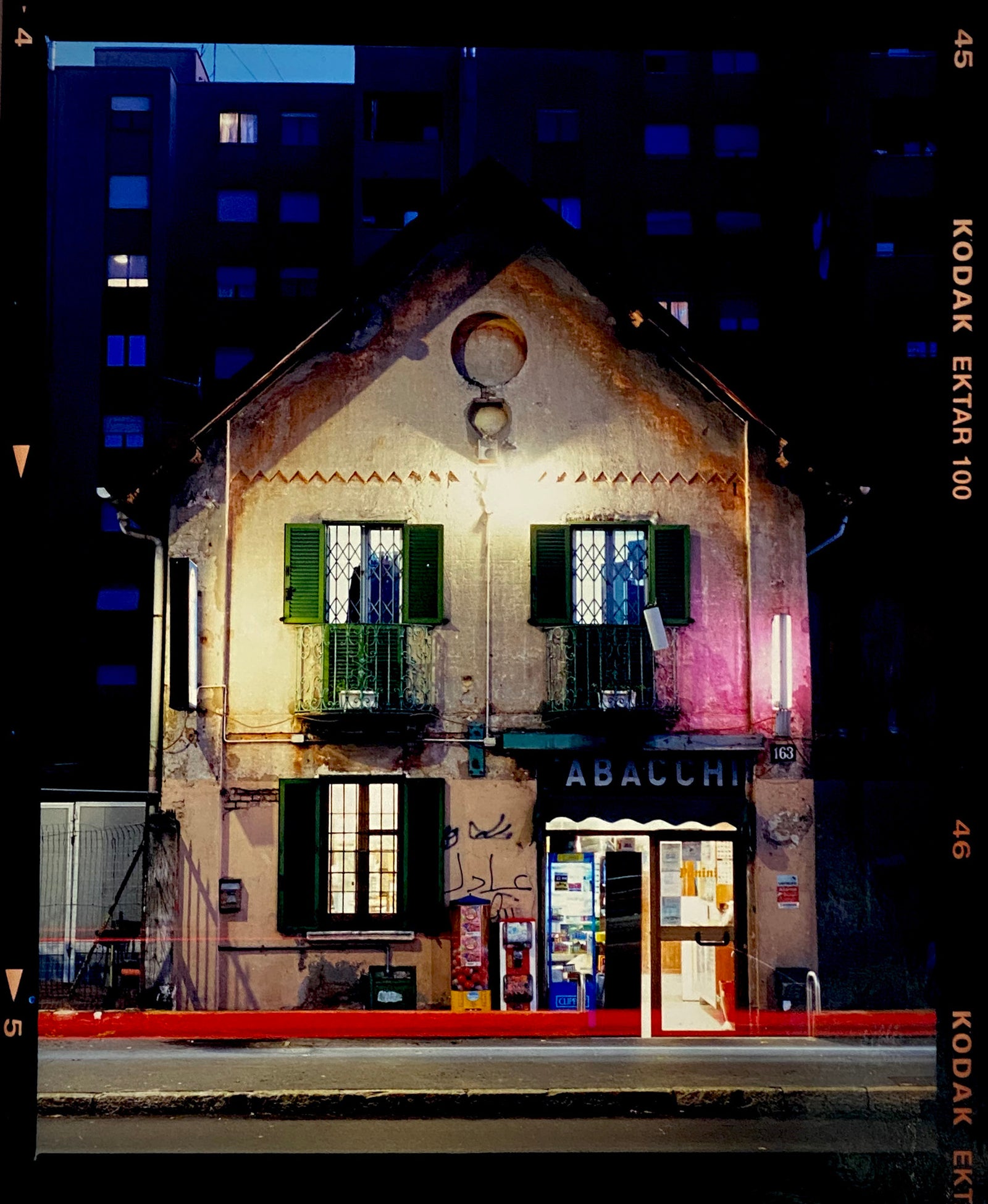The traditional Italian Tobacconist shop, here in a Swiss Cottage style building set against a vast urban apartment block.