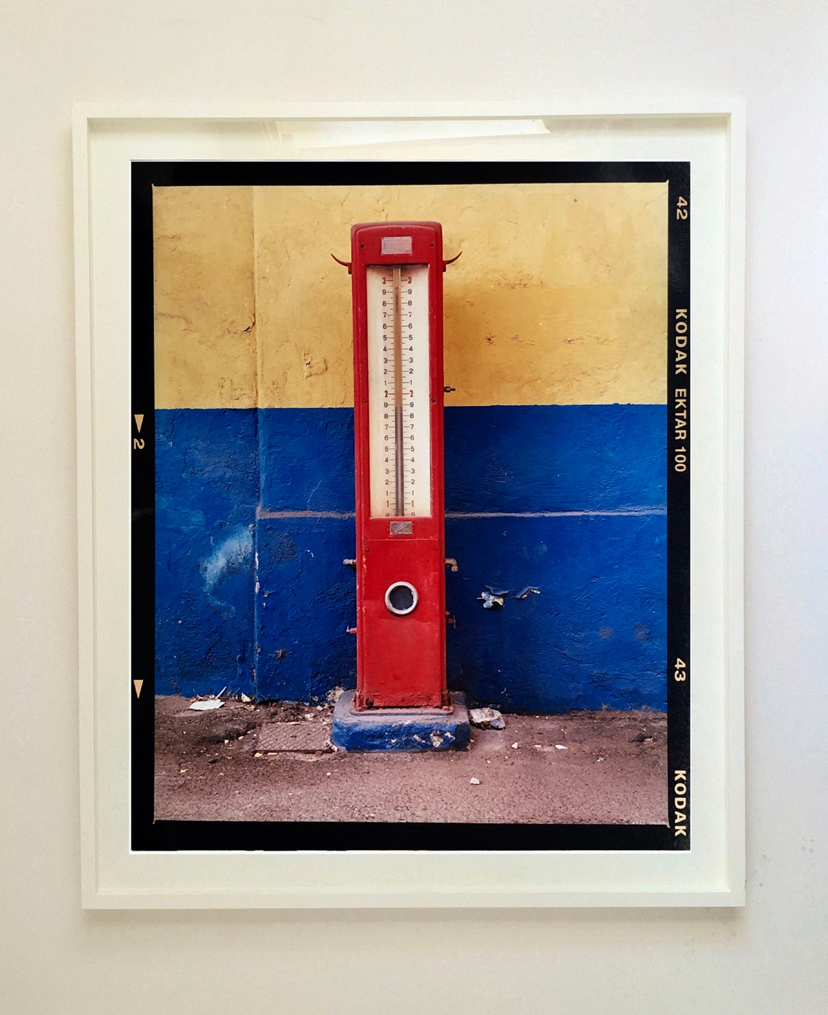 A red retro tyre pump against a yellow and blue painted wall, in the Porta Genova area of Milan.