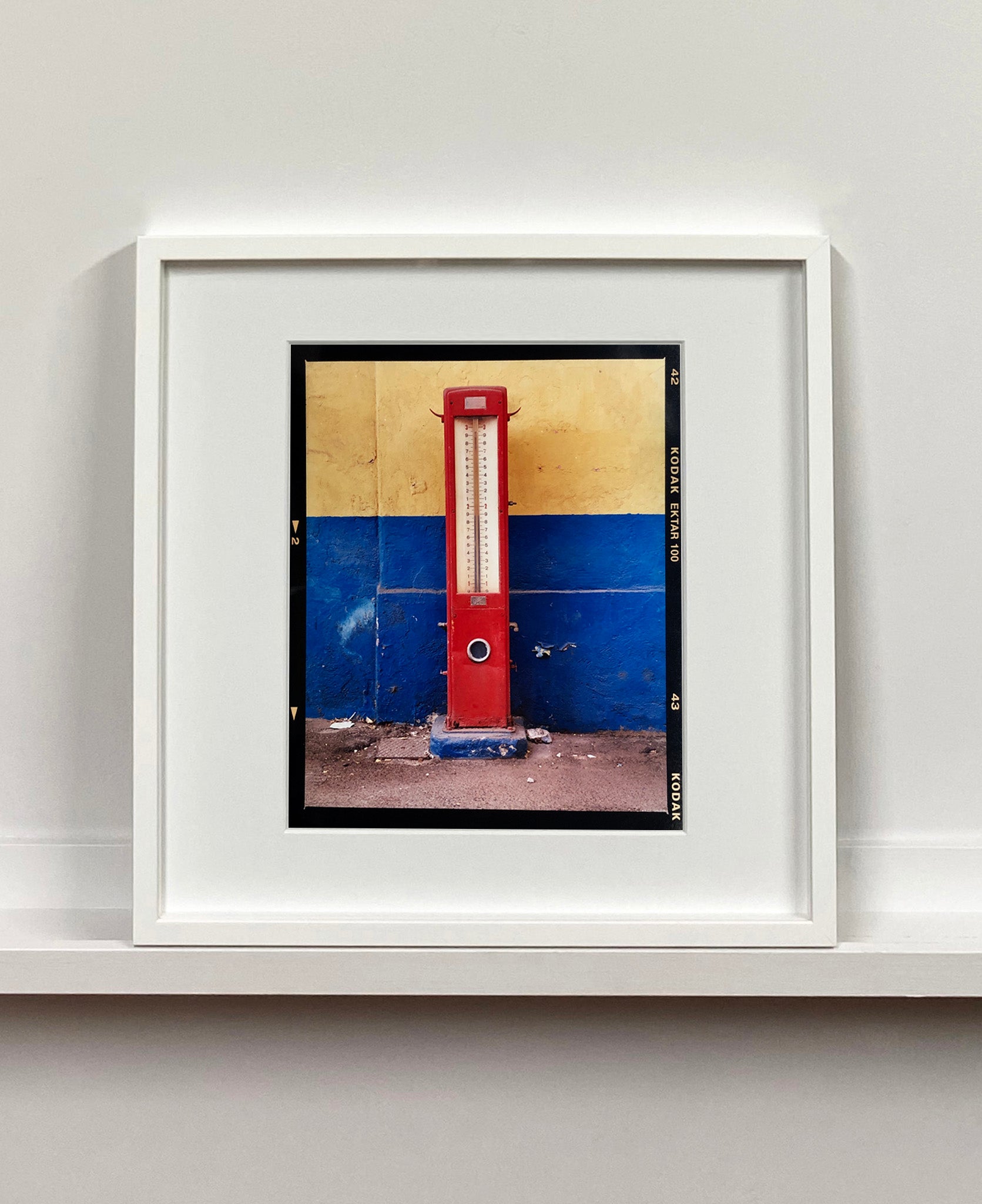 A red retro tyre pump against a yellow and blue painted wall, in the Porta Genova area of Milan.